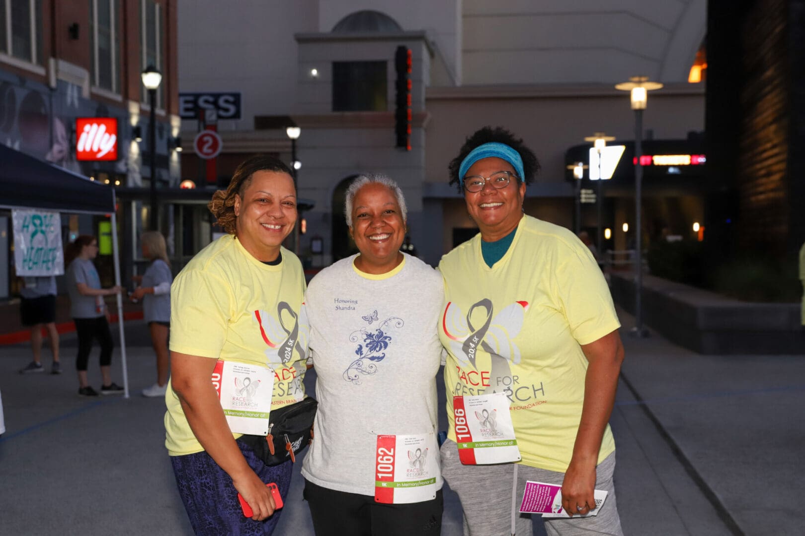 Three women smiling together at a charity walk event.