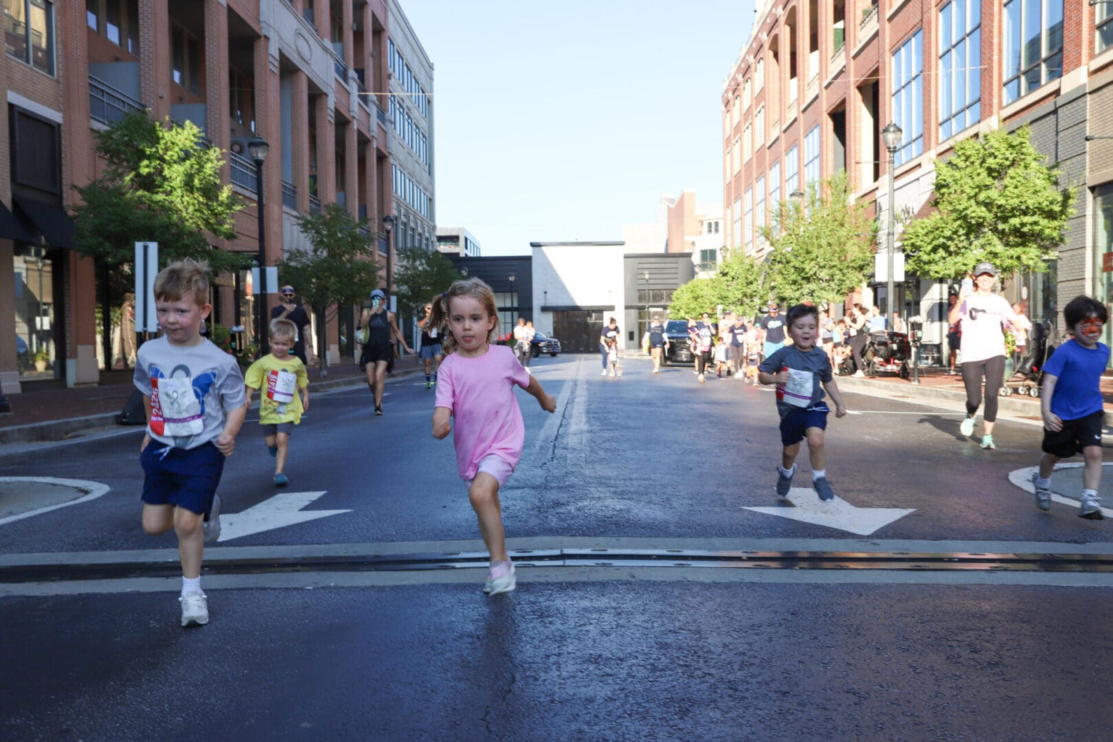 Children running in a street race during a sunny day.